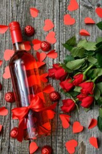 Glass bottle of rose water beside fresh rose petals